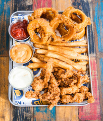 close-up shot of a tray of fries with chicken strips and calamari fritters