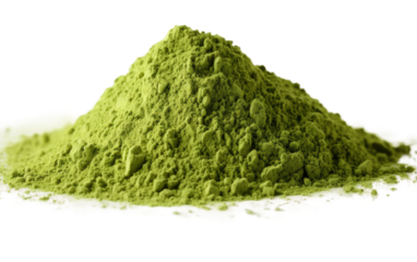 A mound of vibrant green powder sits prominently on a clean white surface, creating a striking contrast. The fine particles are heaped together in a shapeless pile, casting a shadow beneath them.