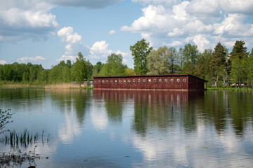 Wooden boathouse on the bank of the lake with reflection in water