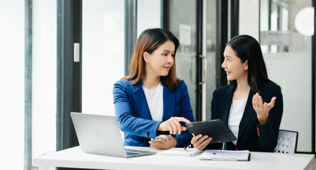 Businesswoman leading team meeting and using tablet and laptop computer with financial in office