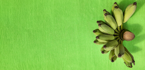 Bunch of green bananas on a vibrant green background with copyspace for text, suitable for healthy...