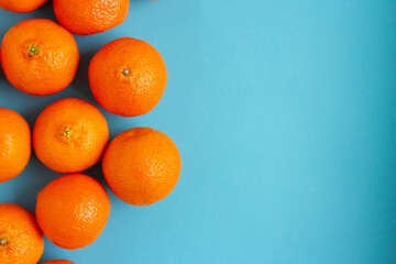 Many fresh orange fruits on left side of light blue background. Vibrant horizontal photo of citrus...