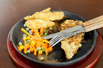 Crispy chicken steak served on hot plate mixed with carrot, potato, and other vegetables