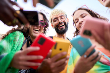 A group of happy people is celebrating and sharing a fun moment using mobile with their colorful...