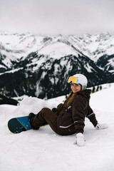 Fototapeta na wymiar girl snowboarder learns to ride a snowboard. winter sport. ski slope. active winter holiday. equipment and snowboard. winter alps landscape