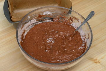 Szklana miska z surowym ciastem czekoladowym brownie na kuchennym blacie - obrazy, fototapety, plakaty