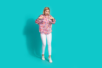 Full size photo of astonished girl wear oversize shirt white trousers look down at empty space isolated on turquoise color background