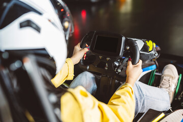 closeup detail of teenager grabbing the steering wheel of the karts in the race on the asphalt track