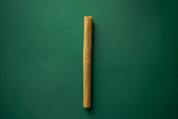 A neatly rolled cannabis joint on a vibrant green background, overhead flat lay studio shot