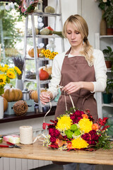 Girl florist makes bouquet on the table in the salon.