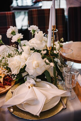 Plate with napkin and glass on dining table, luxury rich decor. Flowers decor on table. Wedding set up, dinner table reception in restaurant. Serving, setting table in hall. Birthday, baptism, event.
