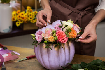 Obraz na płótnie Canvas Florist makes an arrangement of pumpkins and flowers