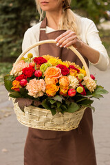 Girl florist holding a basket of flowers in her hands