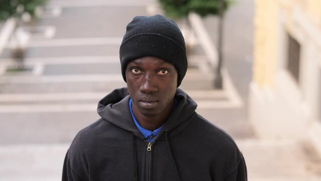 African Migrant in Hat and Hoodie Looking Sad