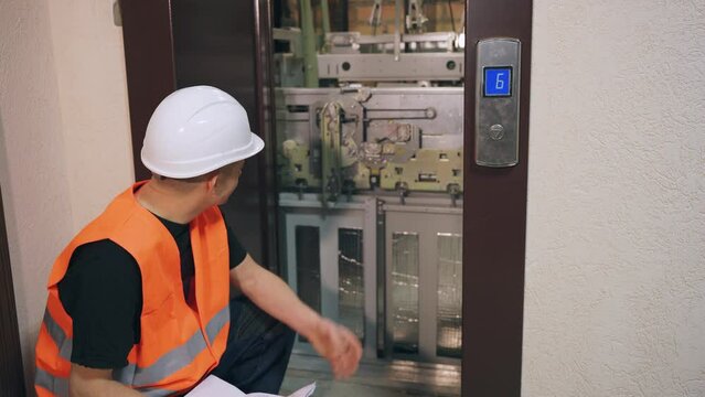 Complex modern elevator equipment, the engineer solves the problem and thinks about which part to replace. The male worker is upset that he does not know how to fix the problem.