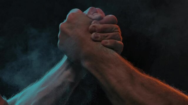 Sporty handshake of two muscular men on black background
