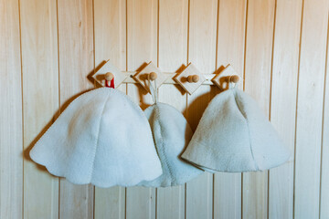 Three white bridal party hats on hooks in a wooden sauna