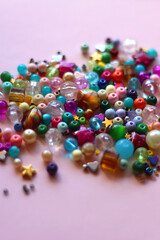 Various colorful beads on bright pink background. Selective focus.