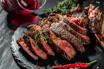 Selbstklebende Fototapeten Steakhouse sliced rib eye Tomahawk beef veal steak with red wine on a dark background. top view. copy space for text  © Надія Коваль