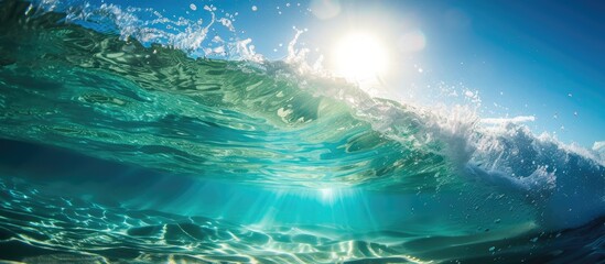 Fototapeta premium The sun shines brightly over the clear ocean waves during summertime, reflecting its rays on the surface and under the blue waters, creating a stunning sight.