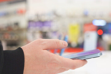 Hand of male buyer testing smartphone in electronics store