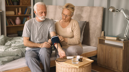 Senior couple measuring blood pressure at home