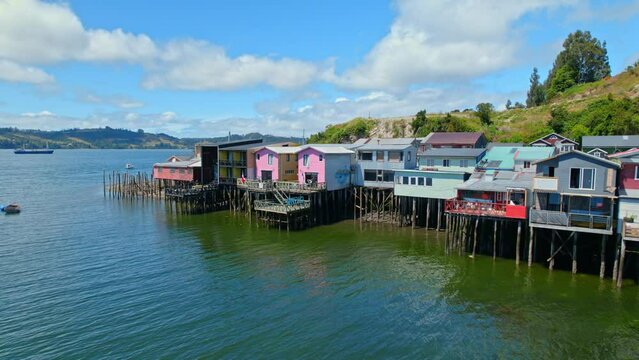 Stilt houses of Castro in Chiloe, colorful houses on the water dolly out, Chile. Sunny day establishing