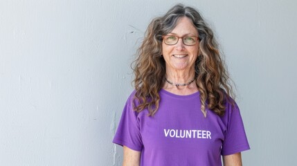 Woman with curly hair glasses and a purple shirt with 'VOLUNTEER