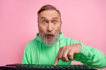 Photo portrait of handsome senior man amazed press key texting keyboard dressed stylish green garment isolated on pink color background