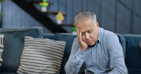 Asian India retired old elder gen x tired upset sad man sitting alone sofa couch feel bad sorrow indoor home Indian aged older adult tense lost male think lonely suffer ill sick health room house