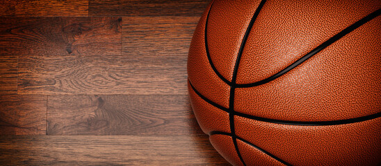 An orange basketball lies on the wooden floor.[
