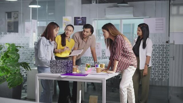 Indian Asian Hindu busy boss lady talk share idea plan use laptop teen girl boy team listen indoor job office young adult gen z female male teach work man staff group leader have client online meeting