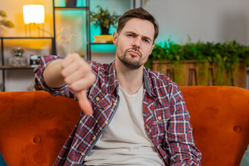 Dislike. Upset unhappy young man showing thumbs down sign gesture, expressing discontent,...