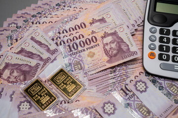 Hungarian forint banknotes are spread out and sorted on a table, with gold bars next to a...