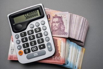The Hungarian forint banknotes are spread out and sorted on a gray table with a calculator next to...