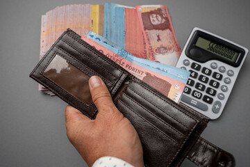 A man puts Hungarian forints in his wallet. The man holds Hungarian money on the table and in his...