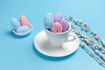 Cup with colored Easter eggs on the blue background.