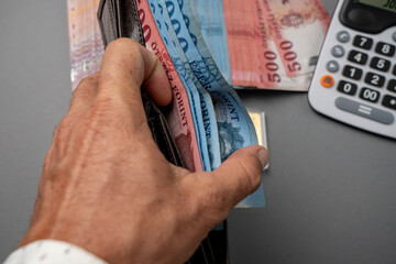 A man puts Hungarian forints in his wallet. The man holds Hungarian money on the table and in his...