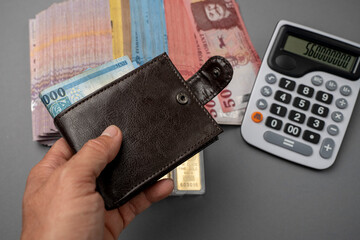 A man puts Hungarian forints in his wallet. The man holds Hungarian money on the table and in his...