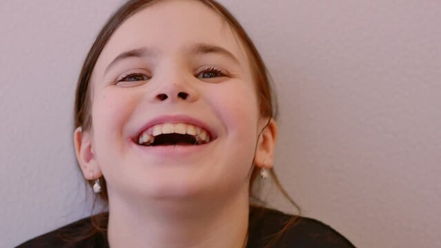 Portrait of a little girl in close-up looking into the frame with herpes inflammation on her lips, a viral disease. Chapped, reddened lips peel off. The child grimaces, laughs.