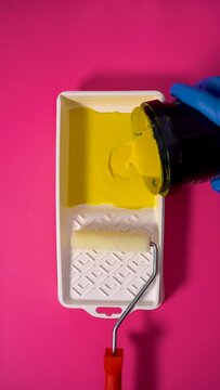 Pouring Yellow Paint Into a White Paint Tray on Vivid Pink Background, Vertical Video