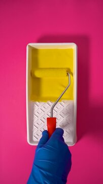 Vivid Yellow Paint Roller in White Container on Pink Background, Vertical Video