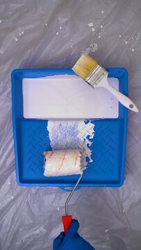 Paint Roller With White Paint Into a Blue Paint Tray on Protected Background, Vertical Video
