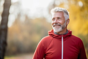 Senior runner jogging outdoors in nature, enjoying the warm weather and fresh air. Fit, active elderly man exercises regularly.