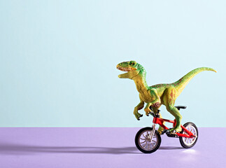 Cute happy green dinosaur riding bike on blue and violet background. Copy space.