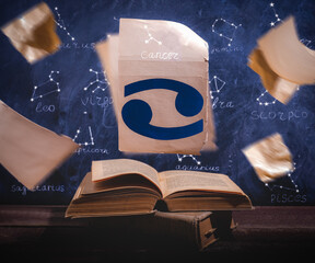 Zodiac sign Cancer on old paper flying above old astrology books.