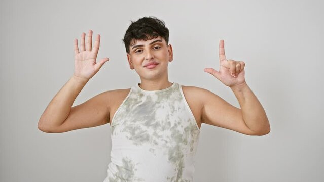 Cheerful young man, wearing a sleeveless t-shirt, confidently smiling while raising hand to point and show the number seven gesture, against an isolated white background