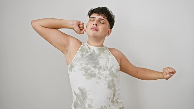 Early morning wake-up stretch, young man wearing sleeveless t-shirt, yawning and stretching for relaxation, standing tired and sleepy against isolated white background.