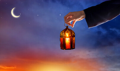 Hand holding  Arabic Ramadan Lantern. Decoration lamp. Crescent moon and the stars. Islamic...
