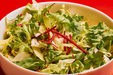 mixed green salad in a bowl on a red background